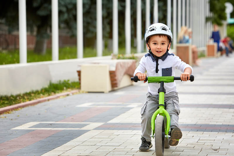 Child boy in white helmet riding on his first bike with a helmet